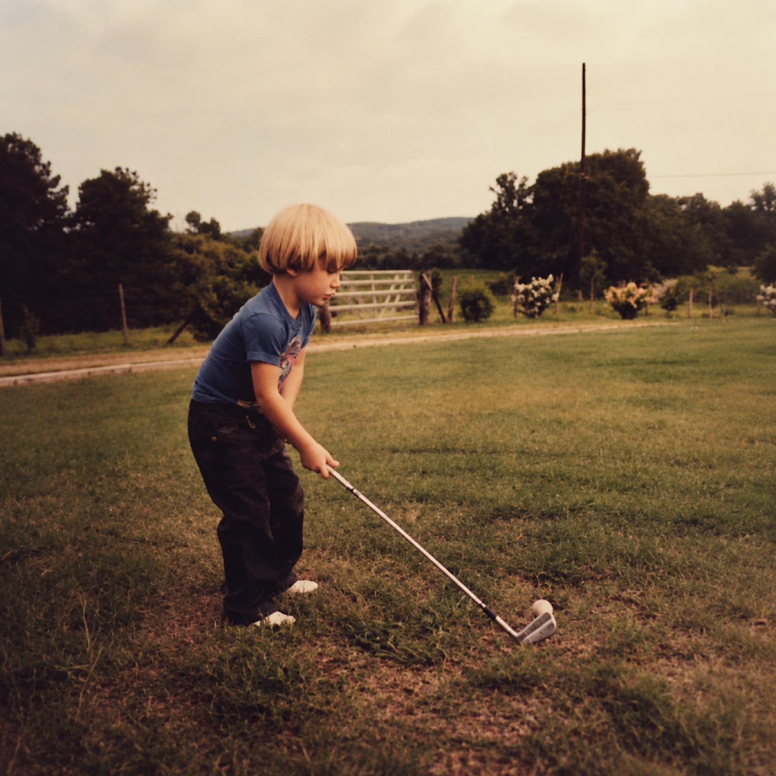 A kid practicing his swing in the front yard